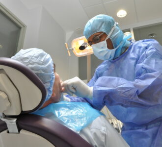 Chirurgien dentiste penché sur un patient, en pleine opération