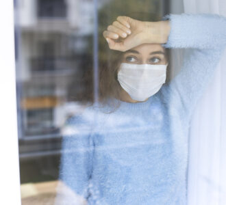 Jeune femme triste et masquée à la fenêtre